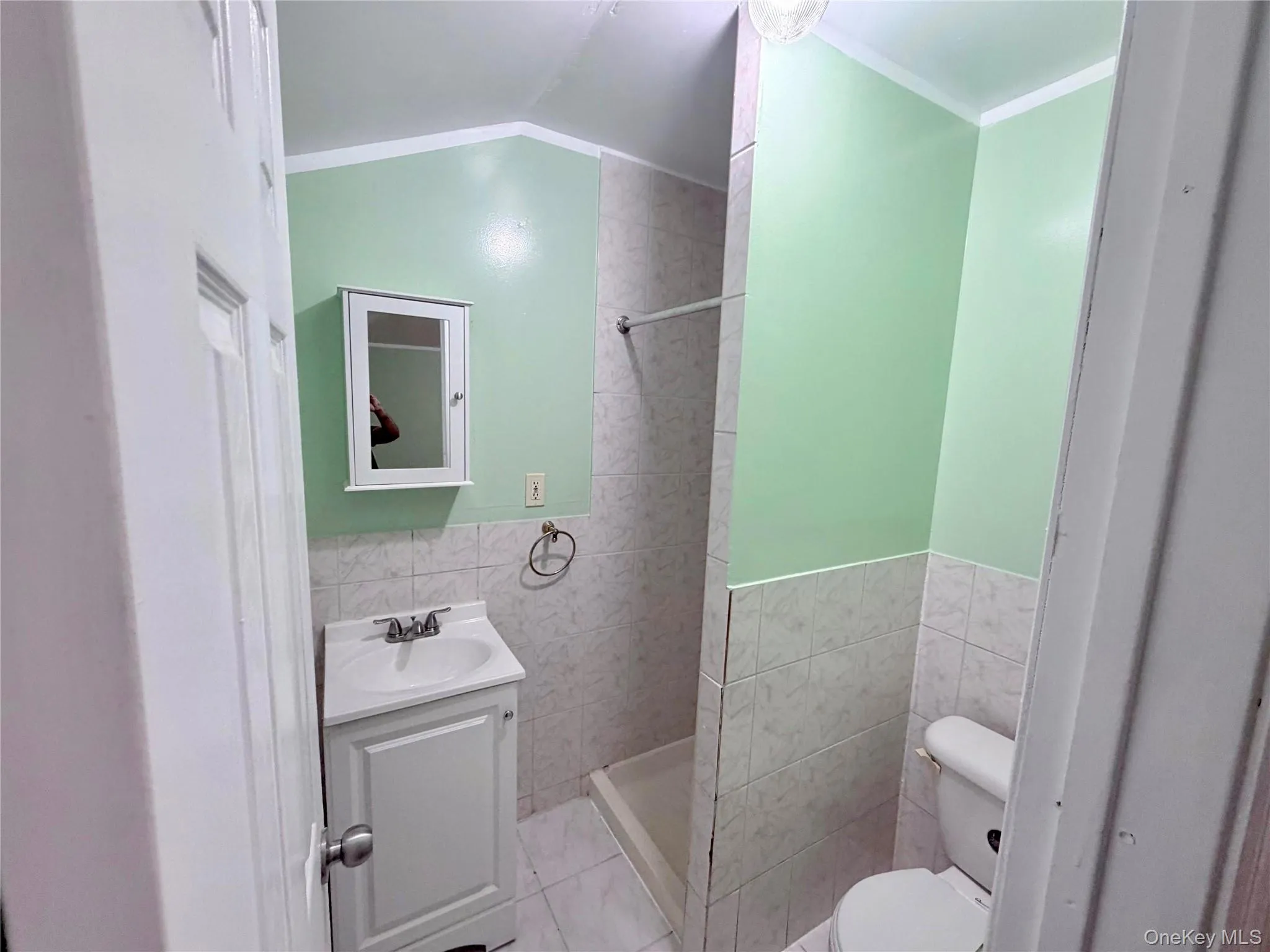 Bathroom featuring tile walls, vanity, a tile shower, wainscoting, and ornamental molding Bathroom featuring tile walls, vanity, a tile shower, wainscoting, and ornamental molding