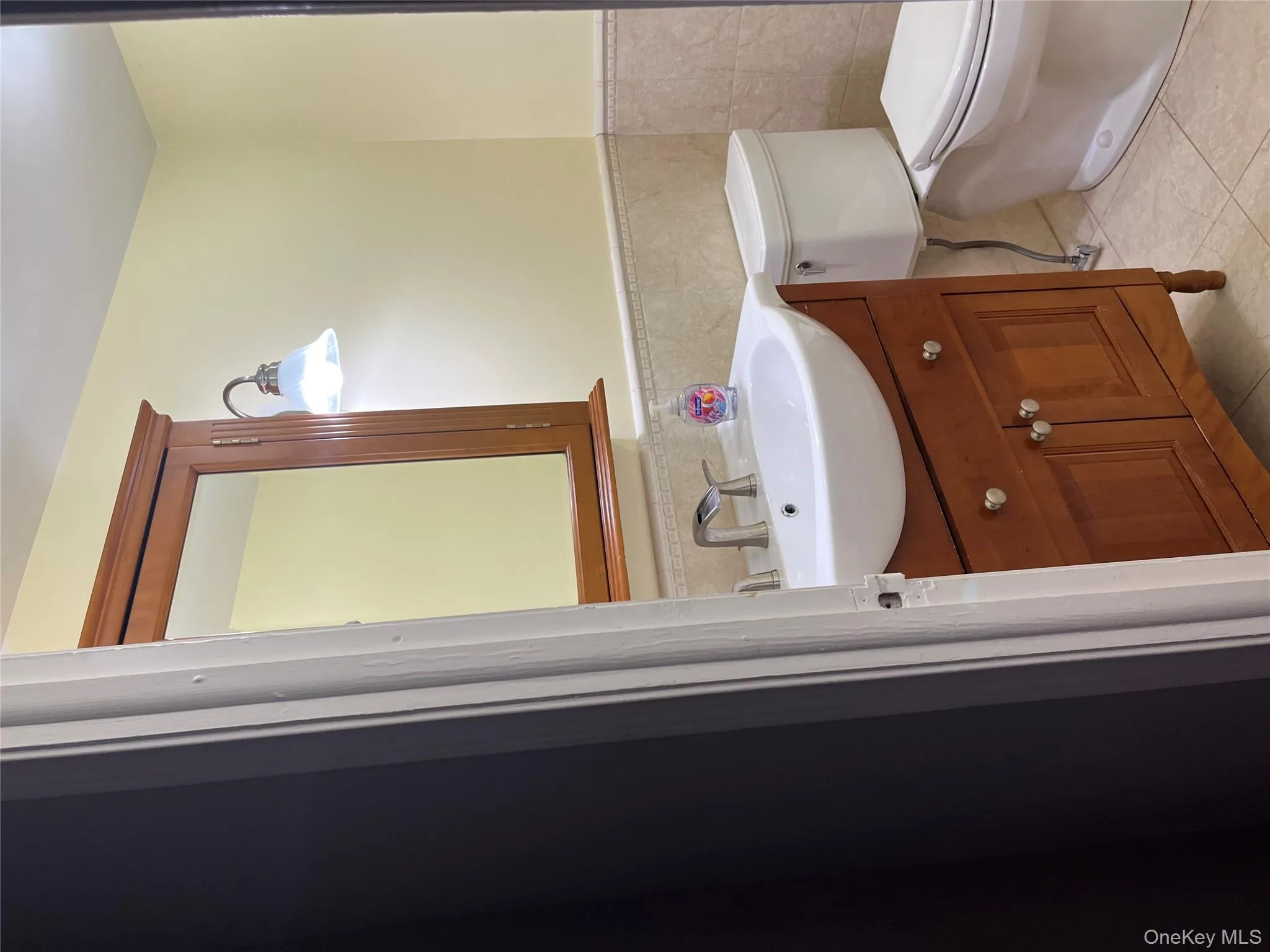 Half bath with vanity, a wainscoted wall, tile walls, and light tile patterned floors Half bath with vanity, a wainscoted wall, tile walls, and light tile patterned floors