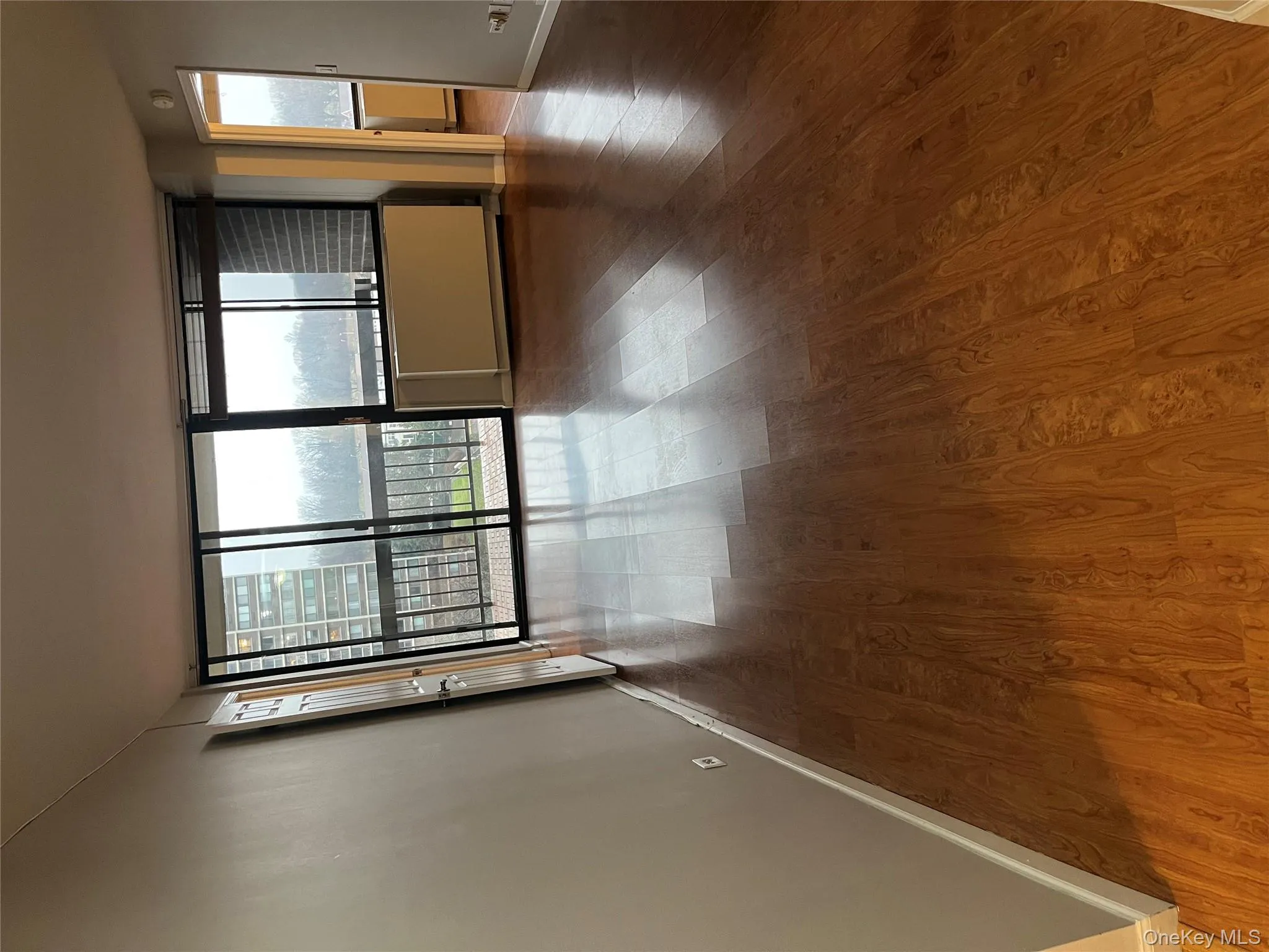 Unfurnished room featuring dark wood-style flooring, floor to ceiling windows, and radiator heating unit Unfurnished room featuring dark wood-style flooring, floor to ceiling windows, and radiator heating unit