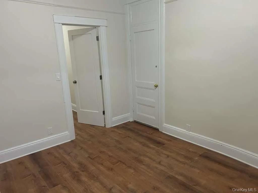 Spare room featuring dark wood-style floors and baseboards Spare room featuring dark wood-style floors and baseboards