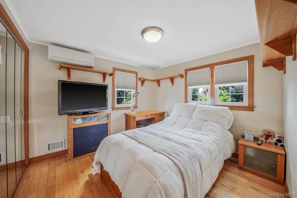 Bedroom with light wood-type flooring, a wall unit AC, and a closet Bedroom with light wood-type flooring, a wall unit AC, and a closet