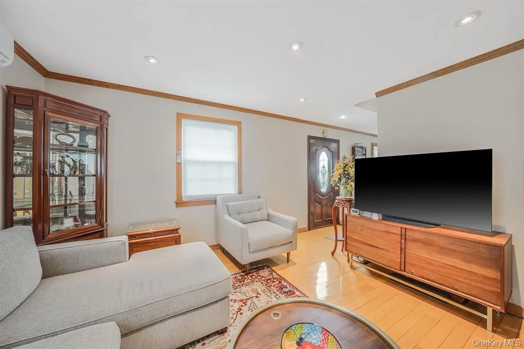 Living area with ornamental molding, recessed lighting, and light wood-type flooring Living area with ornamental molding, recessed lighting, and light wood-type flooring