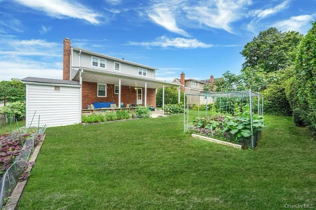 Rear view of house with a vegetable garden, a chimney, and a yard Rear view of house with a vegetable garden, a chimney, and a yard