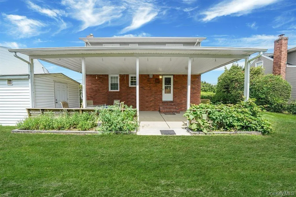 Back of house featuring a porch, a yard, and brick siding Back of house featuring a porch, a yard, and brick siding
