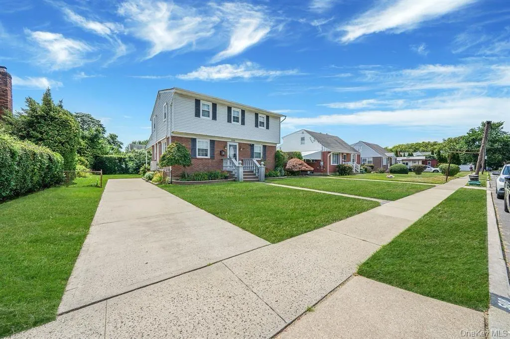 Colonial home featuring brick siding, a front yard, and a residential view Colonial home featuring brick siding, a front yard, and a residential view
