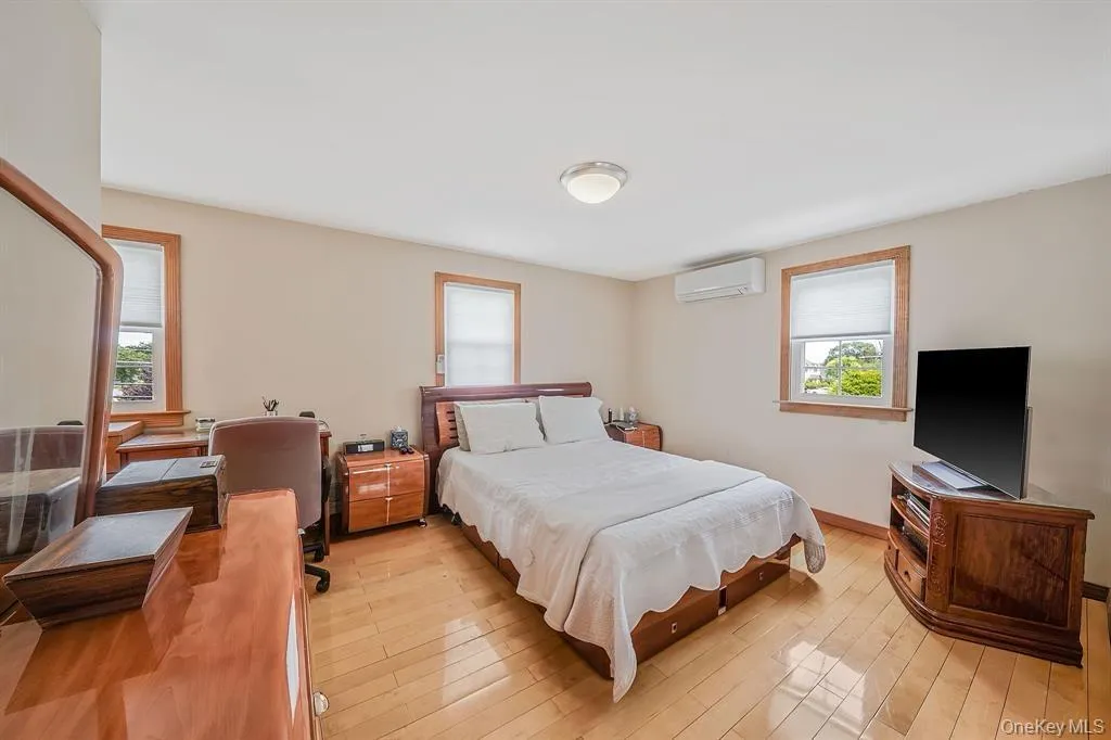 Bedroom with light wood-style floors, multiple windows, a wall unit AC, and a desk Bedroom with light wood-style floors, multiple windows, a wall unit AC, and a desk