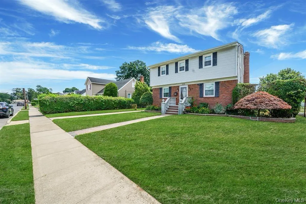 Colonial home with a front lawn and brick siding Colonial home with a front lawn and brick siding