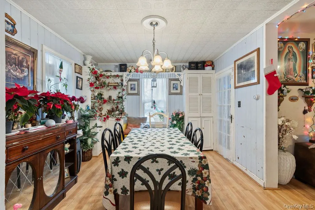 Dining area with ornamental molding, light wood-style flooring, and a chandelier Dining area with ornamental molding, light wood-style flooring, and a chandelier