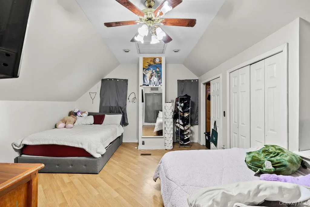 Bedroom featuring a closet, vaulted ceiling, light wood-type flooring, and a ceiling fan Bedroom featuring a closet, vaulted ceiling, light wood-type flooring, and a ceiling fan