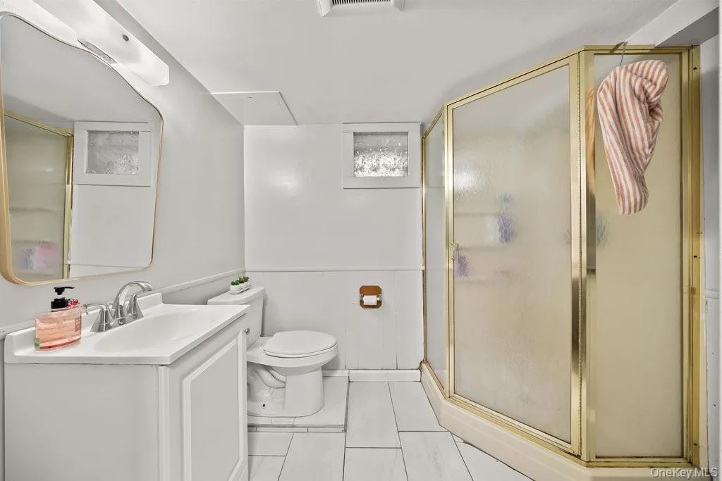 Bathroom featuring a shower stall, vanity, and a wainscoted wall Bathroom featuring a shower stall, vanity, and a wainscoted wall