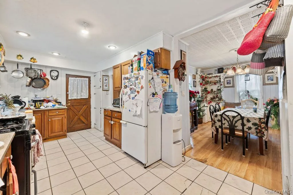 Kitchen featuring brown cabinets, light tile patterned floors, freestanding refrigerator, and light countertops Kitchen featuring brown cabinets, light tile patterned floors, freestanding refrigerator, and light countertops