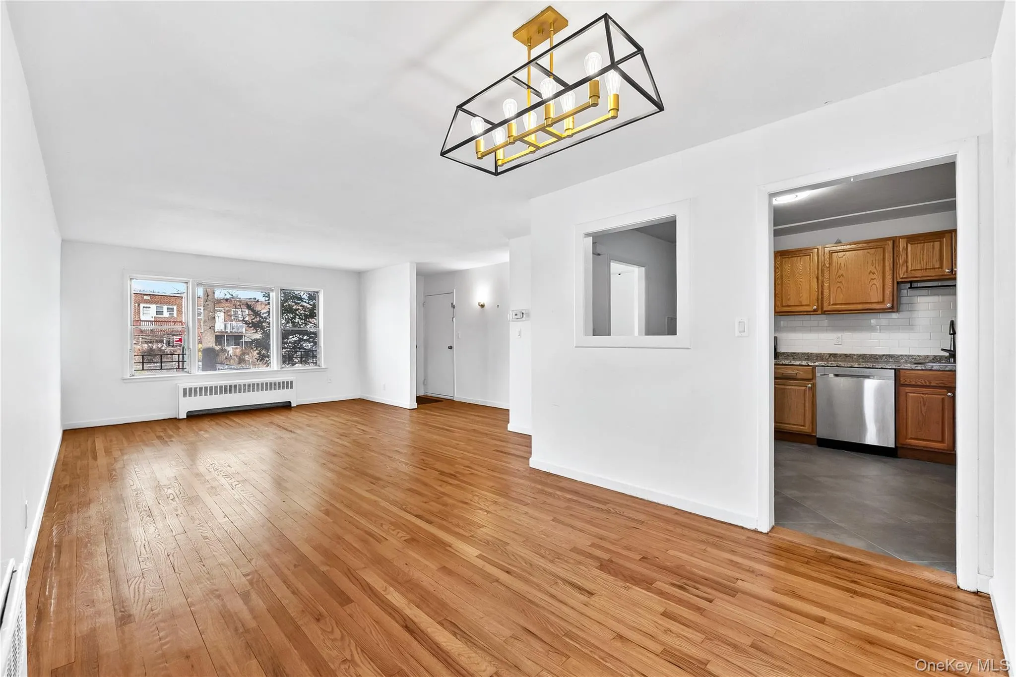 Unfurnished living room with light wood-type flooring, a chandelier, and radiator heating unit Unfurnished living room with light wood-type flooring, a chandelier, and radiator heating unit