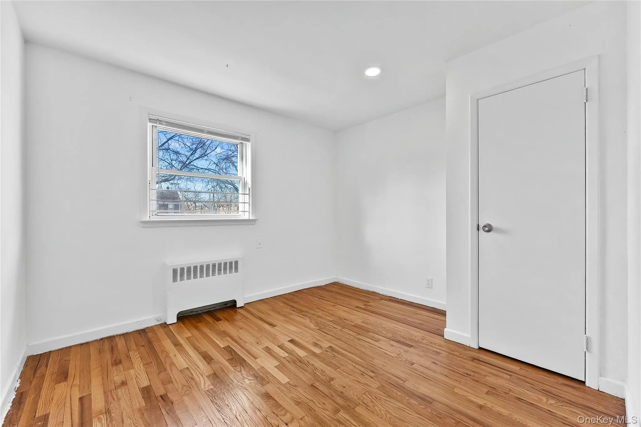 Spare room with radiator heating unit, light wood-style floors, and recessed lighting Spare room with radiator heating unit, light wood-style floors, and recessed lighting