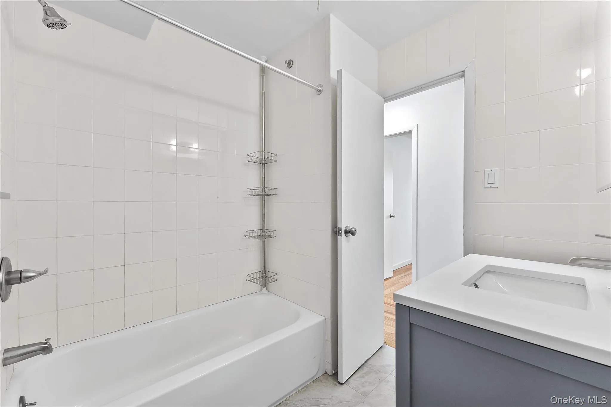 Bathroom with tub / shower combination, vanity, and tile walls Bathroom with tub / shower combination, vanity, and tile walls