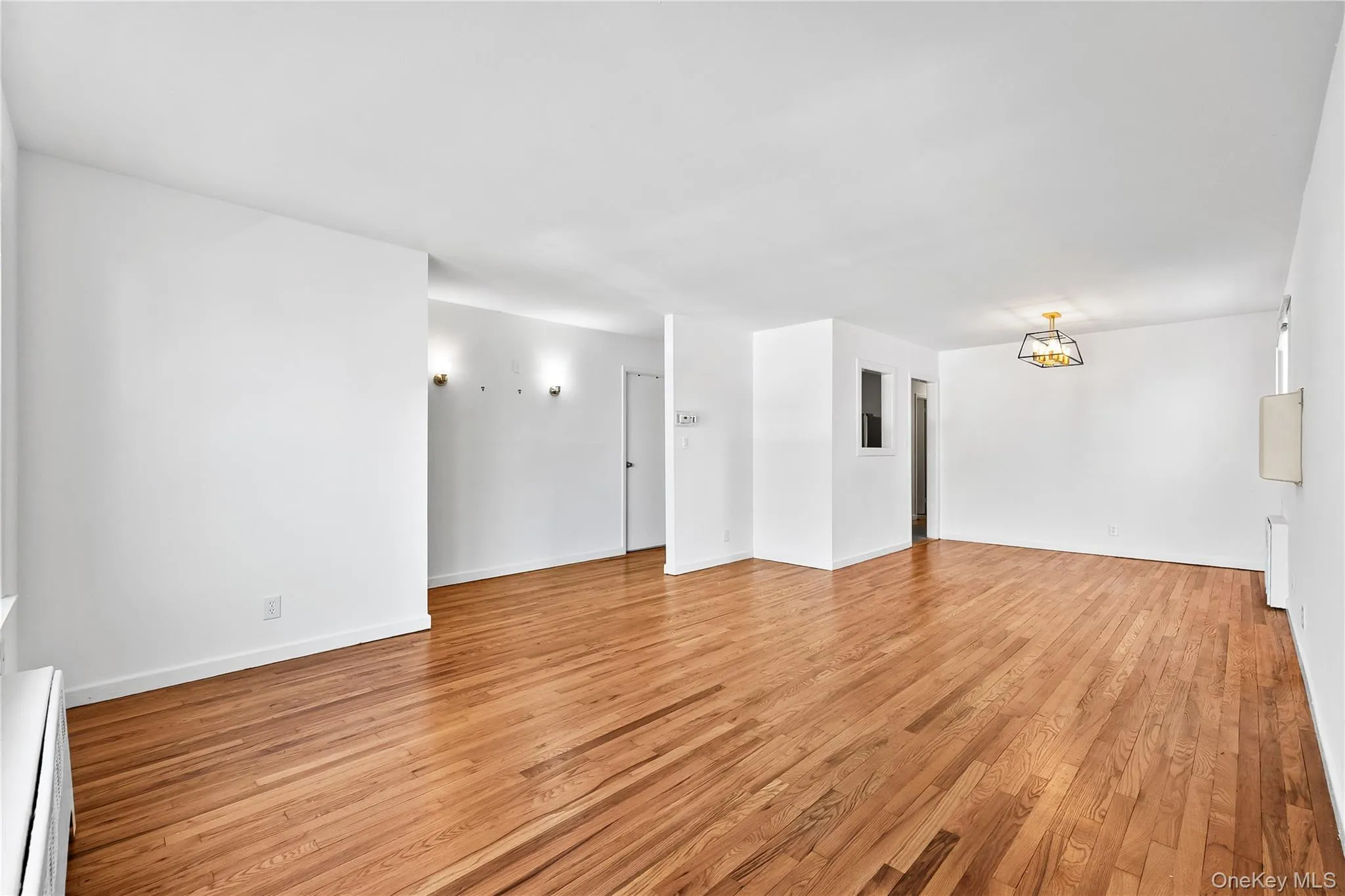 Unfurnished room featuring baseboard heating, light wood-style flooring, and a chandelier Unfurnished room featuring baseboard heating, light wood-style flooring, and a chandelier