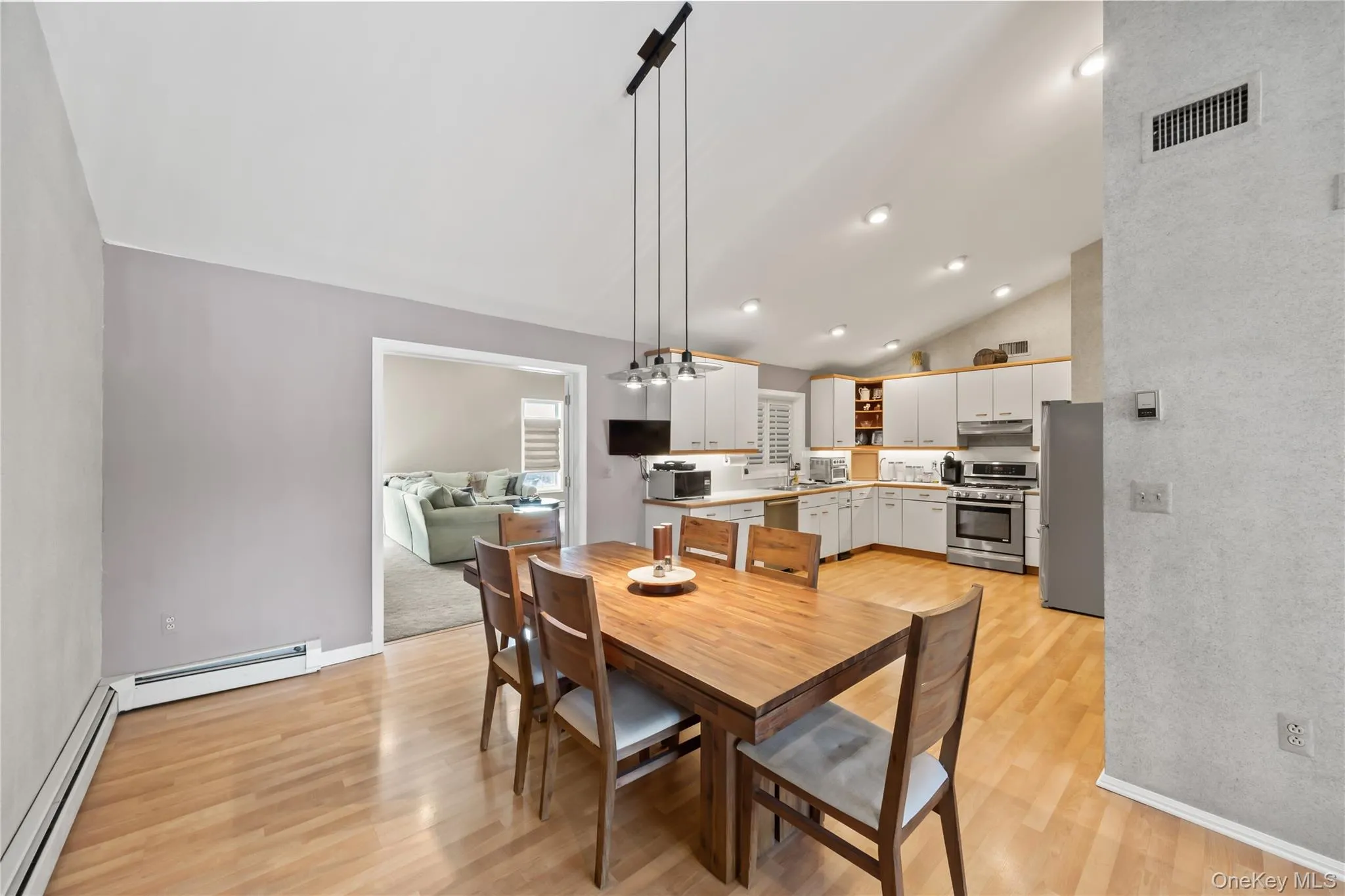 Dining space with lofted ceiling, a chandelier, a baseboard heating unit, light wood-type flooring, and a baseboard radiator Dining space with lofted ceiling, a chandelier, a baseboard heating unit, light wood-type flooring, and a baseboard radiator