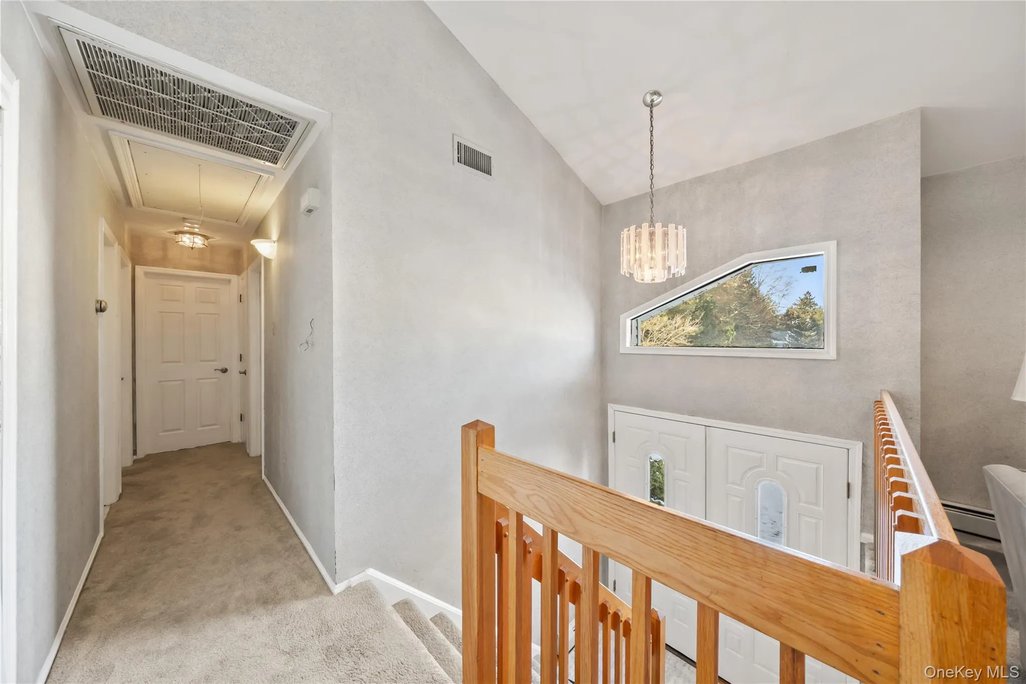 Hall with carpet, attic access, an upstairs landing, a chandelier, and baseboard heating Hall with carpet, attic access, an upstairs landing, a chandelier, and baseboard heating