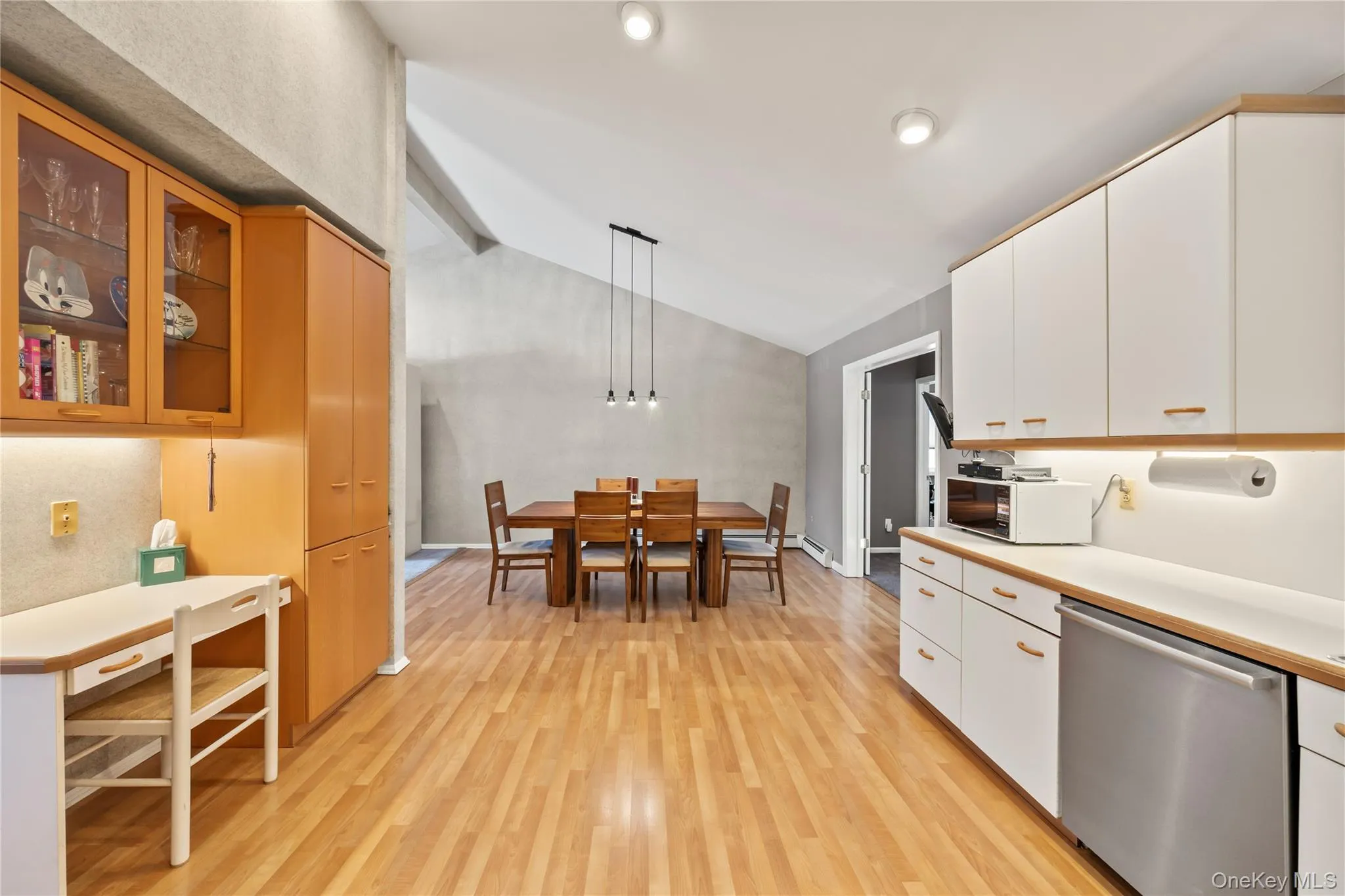 Kitchen with dishwasher, hanging light fixtures, light countertops, vaulted ceiling, and light wood-type flooring Kitchen with dishwasher, hanging light fixtures, light countertops, vaulted ceiling, and light wood-type flooring