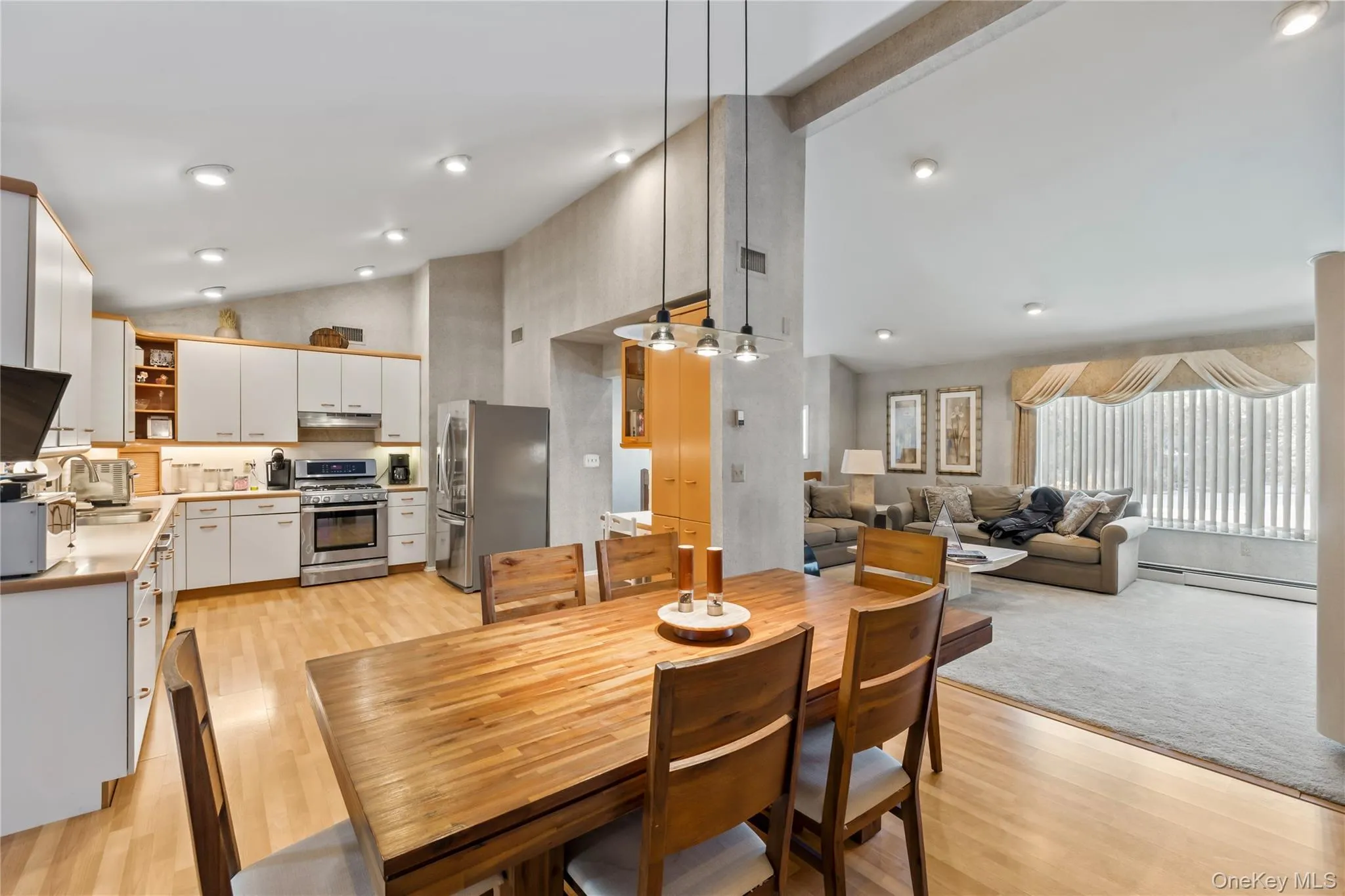 Dining area with light wood-style floors, baseboard heating, and high vaulted ceiling Dining area with light wood-style floors, baseboard heating, and high vaulted ceiling