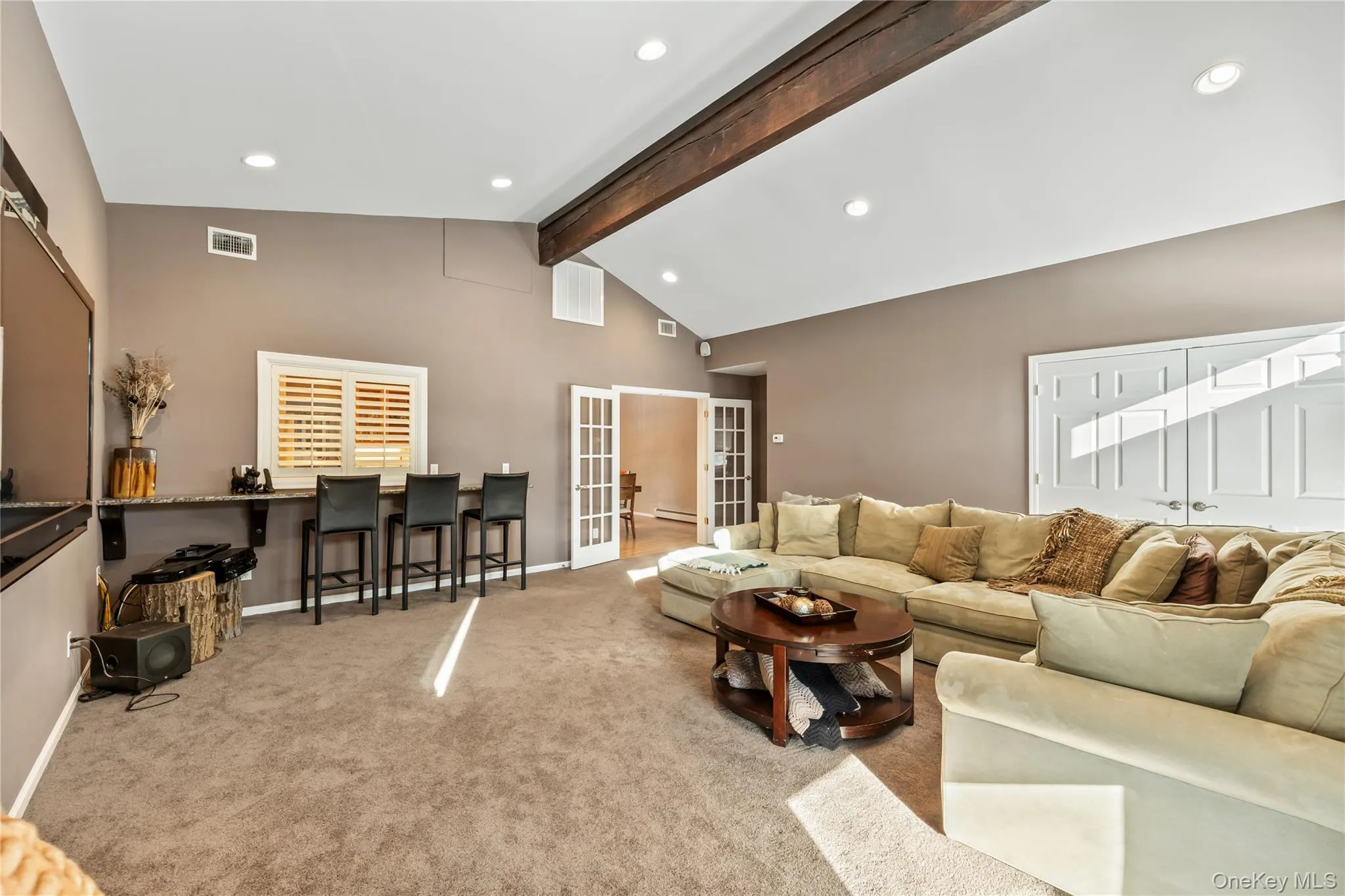 Living room with beam ceiling, french doors, light colored carpet, recessed lighting, and high vaulted ceiling Living room with beam ceiling, french doors, light colored carpet, recessed lighting, and high vaulted ceiling