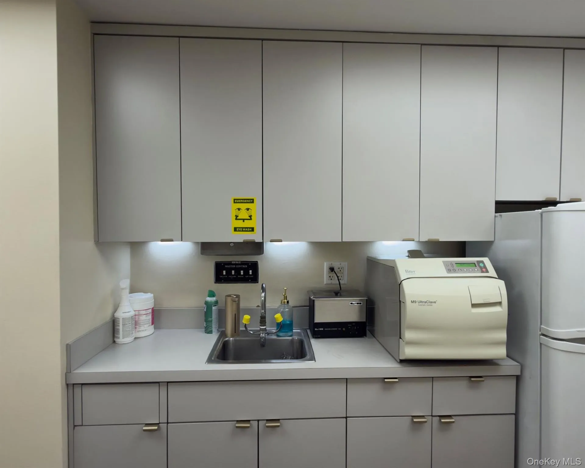 Kitchen featuring light countertops, gray cabinets, freestanding refrigerator, and modern cabinets Kitchen featuring light countertops, gray cabinets, freestanding refrigerator, and modern cabinets