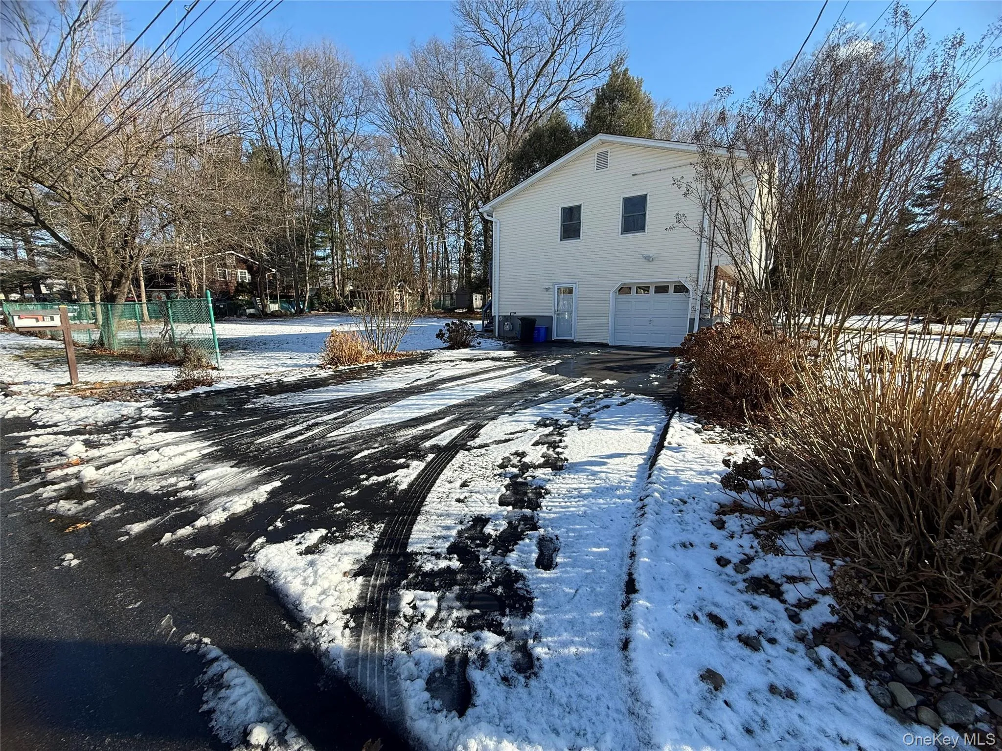 Snow covered property featuring an attached garage and driveway Snow covered property featuring an attached garage and driveway