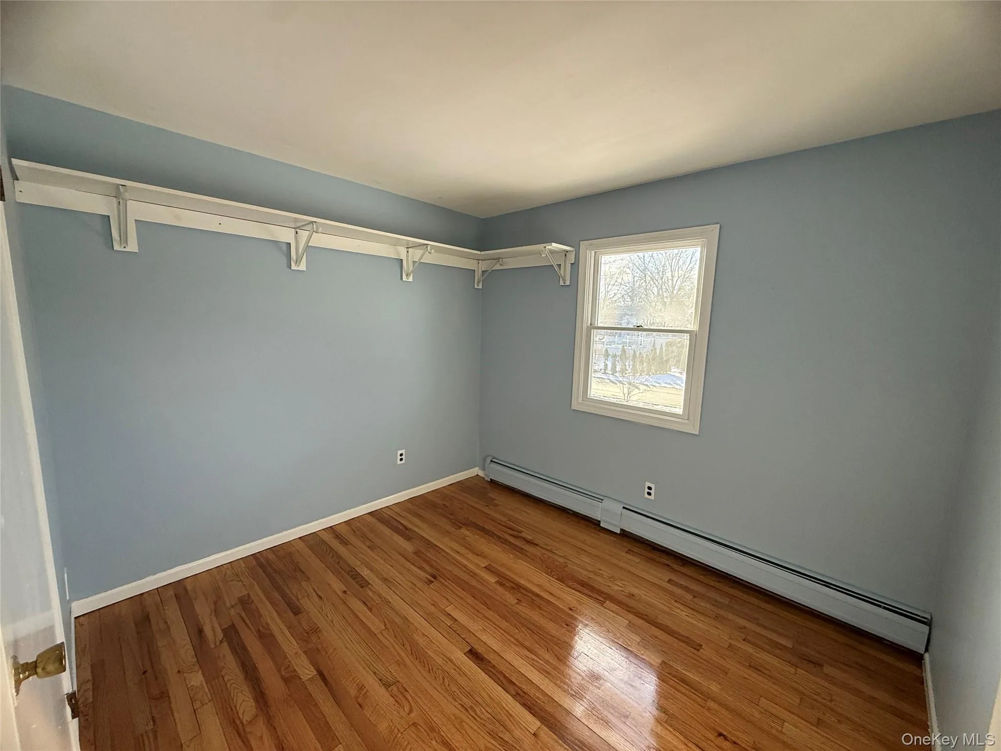 Empty room with a baseboard heating unit and light wood-style flooring Empty room with a baseboard heating unit and light wood-style flooring