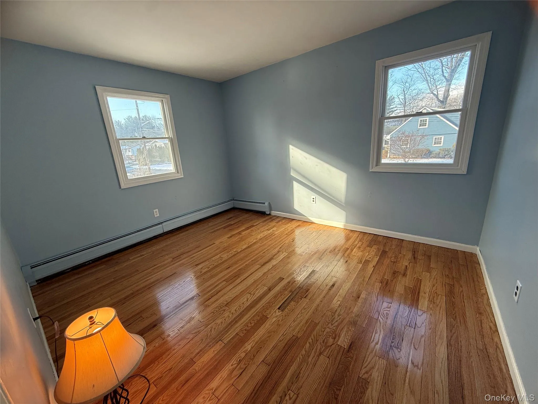 Empty room with plenty of natural light, a baseboard heating unit, and hardwood / wood-style floors Empty room with plenty of natural light, a baseboard heating unit, and hardwood / wood-style floors