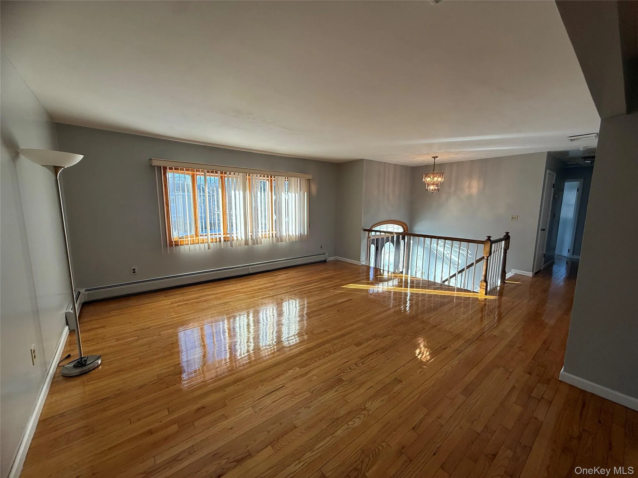 Empty room with a chandelier, hardwood / wood-style floors, and a baseboard radiator Empty room with a chandelier, hardwood / wood-style floors, and a baseboard radiator
