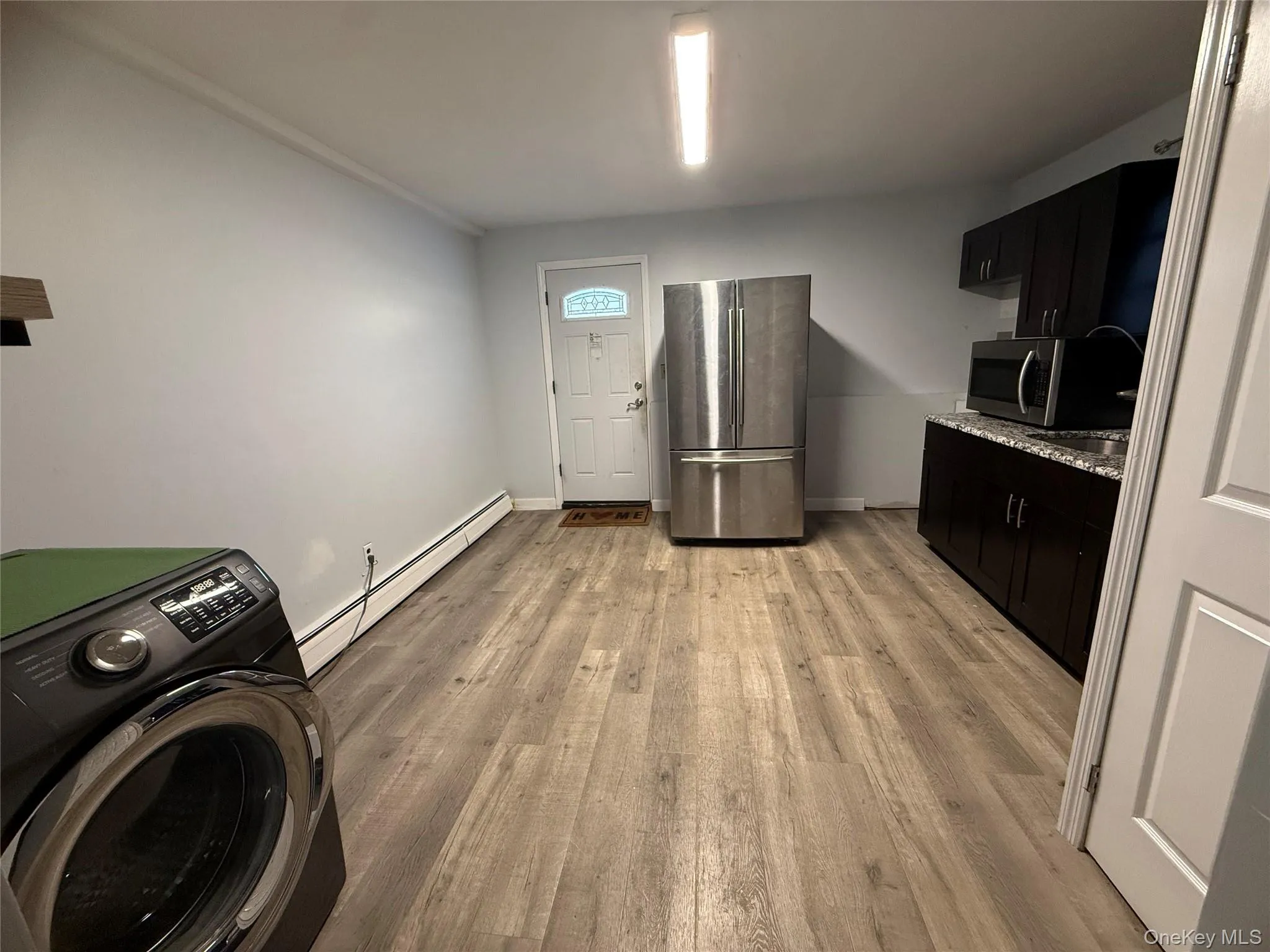 Laundry room with washer / dryer, baseboard heating, and light wood-style floors Laundry room with washer / dryer, baseboard heating, and light wood-style floors