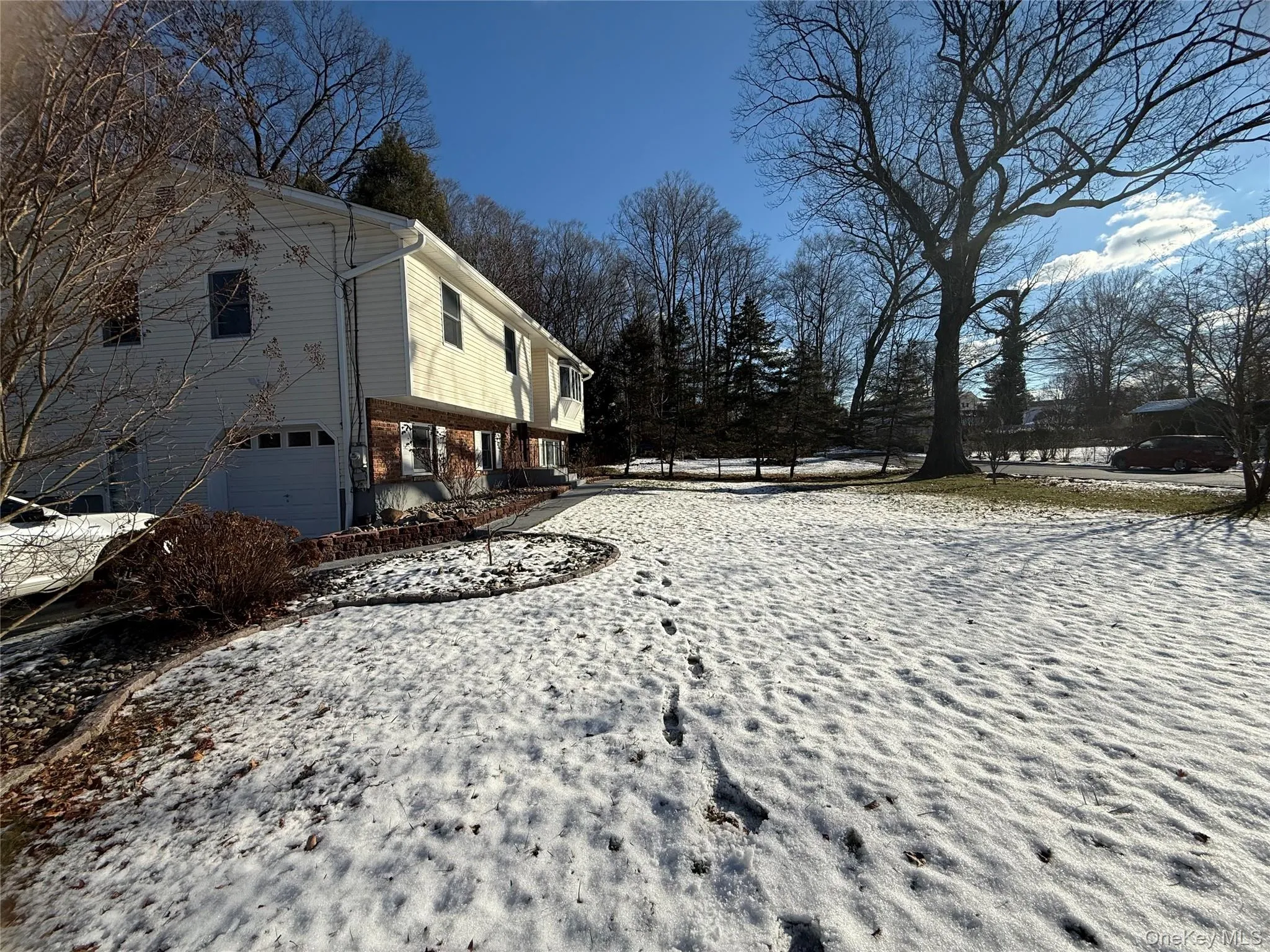 Snow covered property featuring brick siding and a garage Snow covered property featuring brick siding and a garage