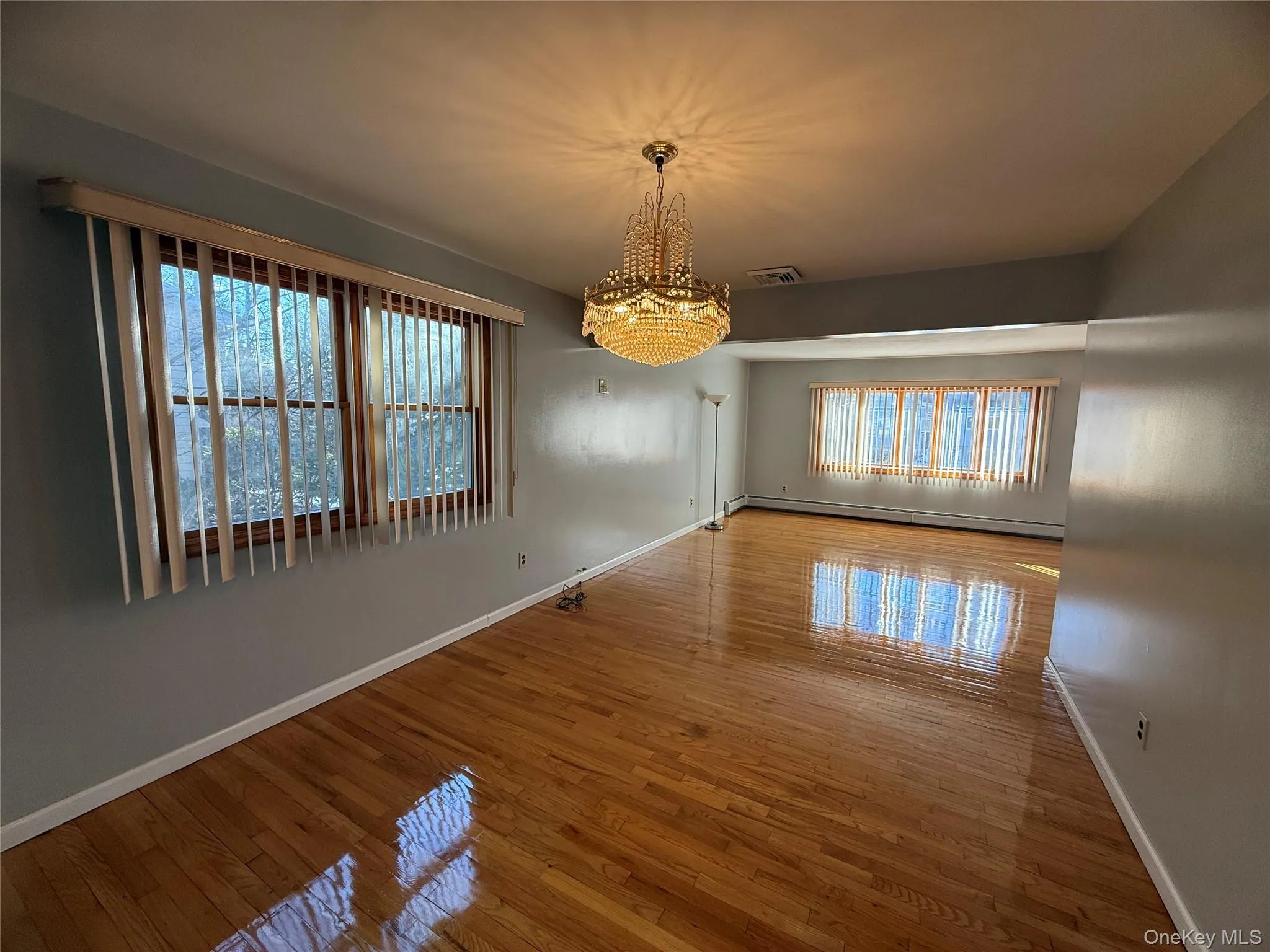 Unfurnished dining area featuring a chandelier, wood-type flooring, and a baseboard radiator Unfurnished dining area featuring a chandelier, wood-type flooring, and a baseboard radiator