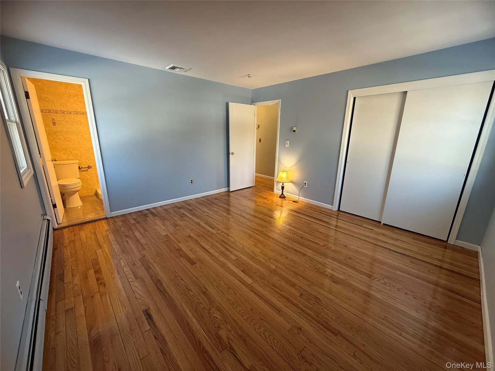 Unfurnished bedroom featuring a baseboard heating unit, wood-type flooring, and a closet Unfurnished bedroom featuring a baseboard heating unit, wood-type flooring, and a closet