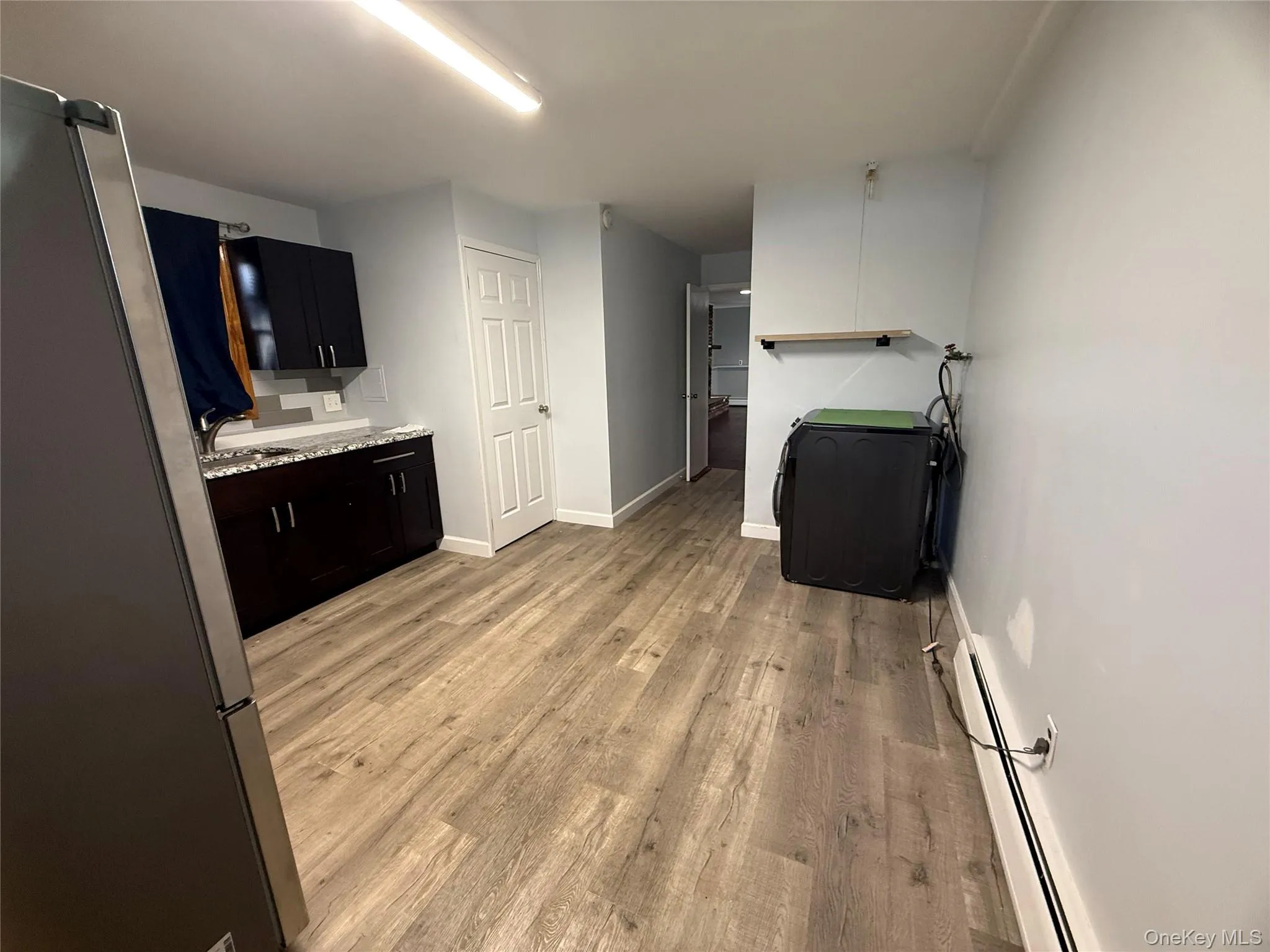 Laundry room with a baseboard radiator and light wood-type flooring Laundry room with a baseboard radiator and light wood-type flooring