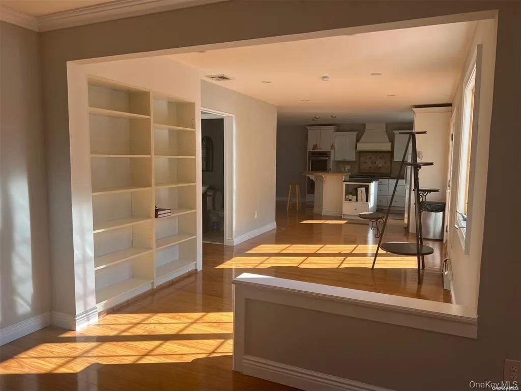 Hallway featuring light wood finished floors and built in shelves Hallway featuring light wood finished floors and built in shelves
