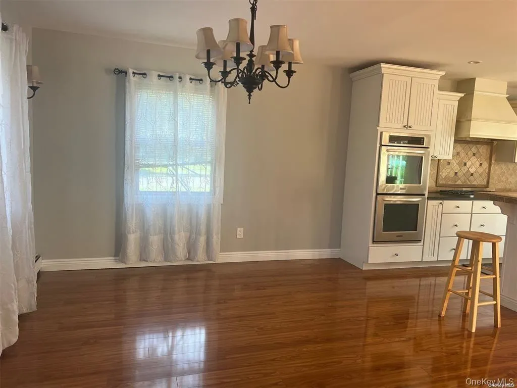 Kitchen with dark countertops, premium range hood, a chandelier, double oven, and pendant lighting Kitchen with dark countertops, premium range hood, a chandelier, double oven, and pendant lighting