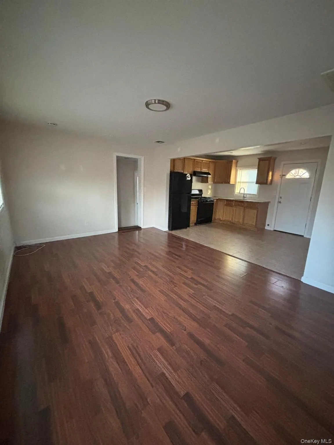 Unfurnished living room featuring baseboards and dark wood-type flooring Unfurnished living room featuring baseboards and dark wood-type flooring