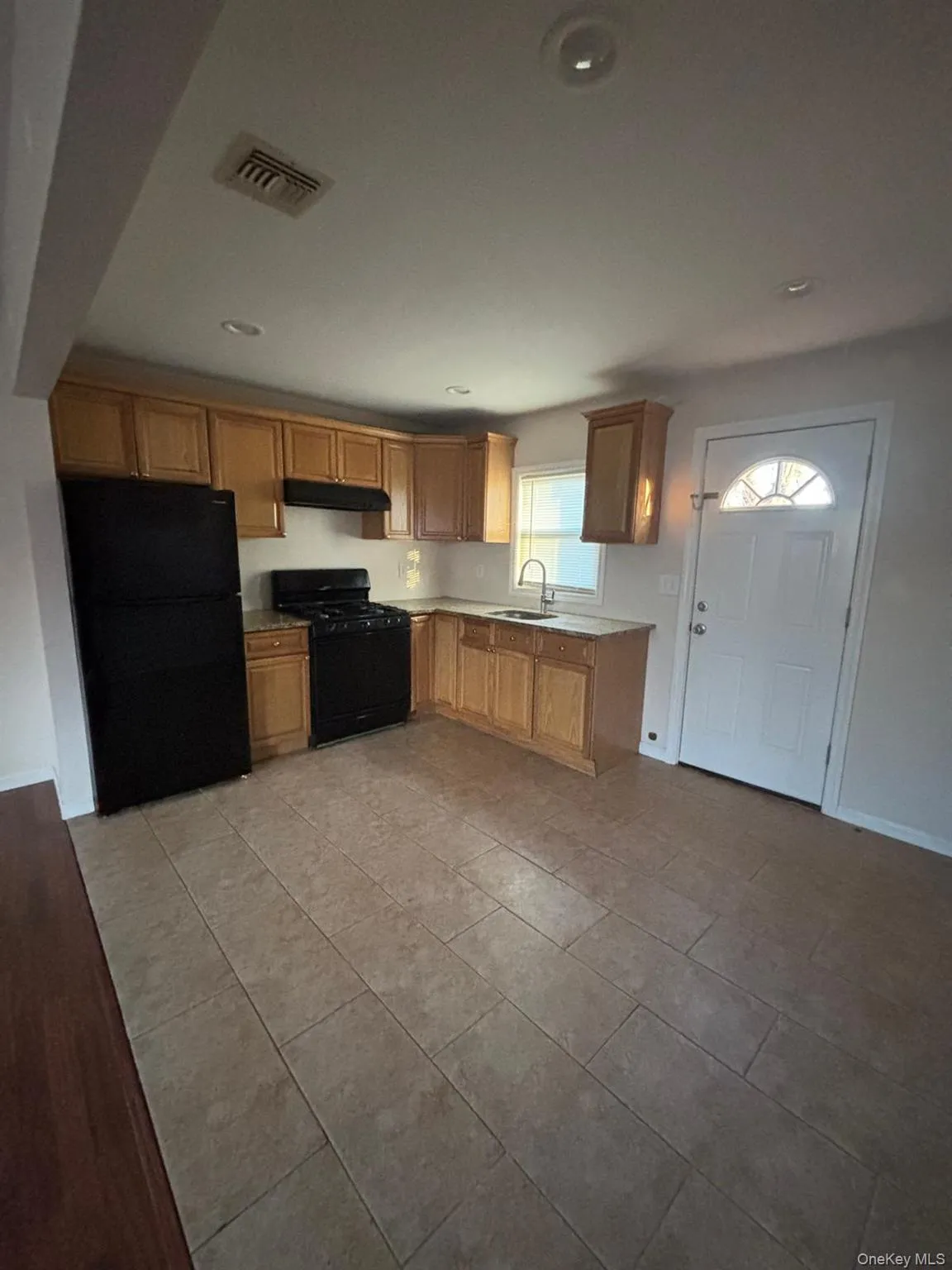 Kitchen with black appliances, light countertops, light tile patterned floors, under cabinet range hood, and recessed lighting Kitchen with black appliances, light countertops, light tile patterned floors, under cabinet range hood, and recessed lighting