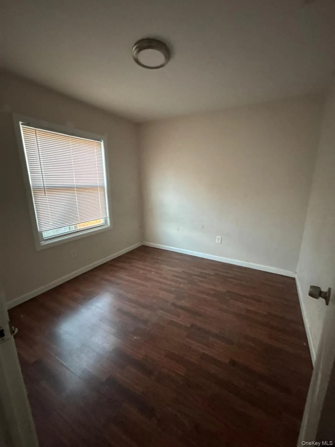 Unfurnished room featuring baseboards and dark wood-style flooring Unfurnished room featuring baseboards and dark wood-style flooring