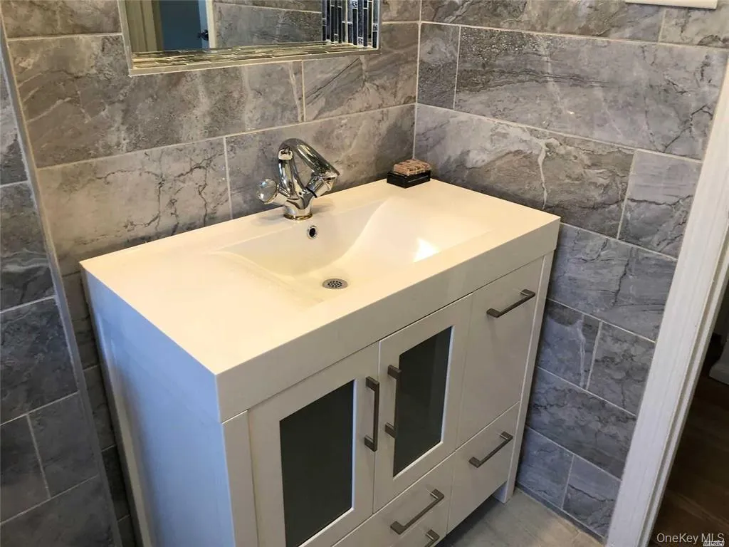 Half bathroom featuring tile walls and vanity Half bathroom featuring tile walls and vanity