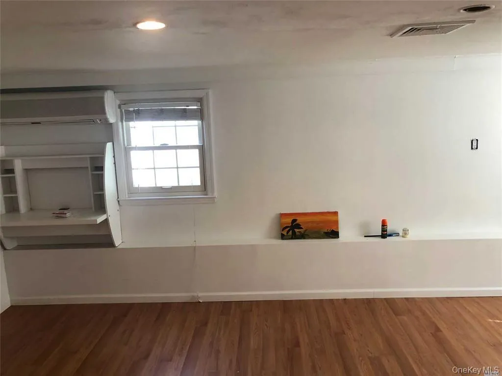 Empty room with dark wood-style floors, a wall mounted AC, and recessed lighting Empty room with dark wood-style floors, a wall mounted AC, and recessed lighting