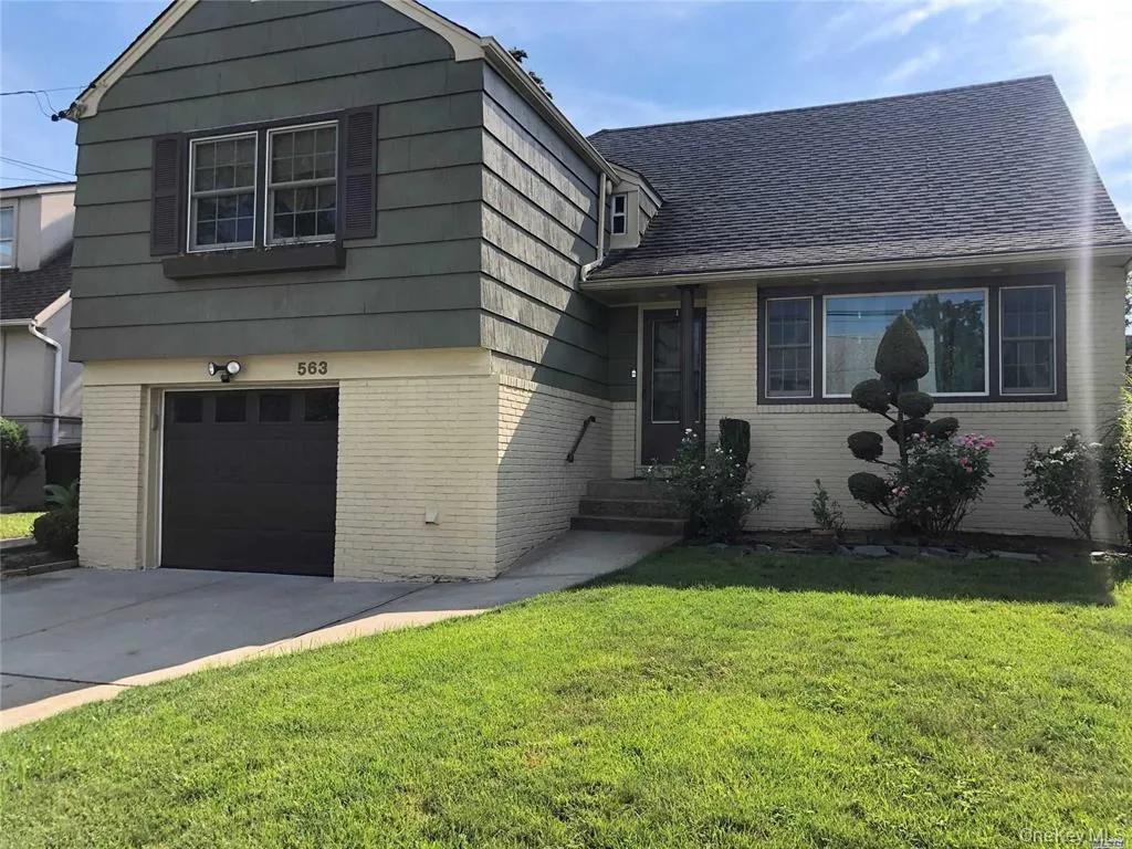 View of front of home with brick siding, a garage, a front yard, driveway, and a shingled roof View of front of home with brick siding, a garage, a front yard, driveway, and a shingled roof