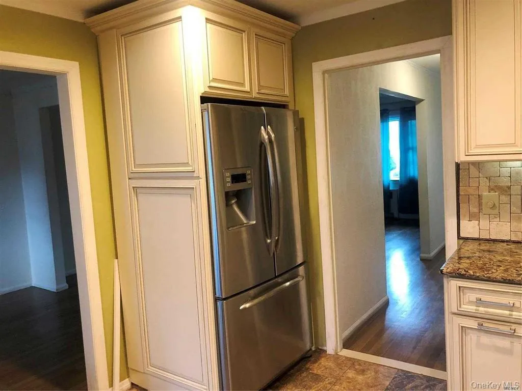 Kitchen featuring stainless steel fridge with ice dispenser, dark wood-style flooring, tasteful backsplash, and dark stone counters Kitchen featuring stainless steel fridge with ice dispenser, dark wood-style flooring, tasteful backsplash, and dark stone counters