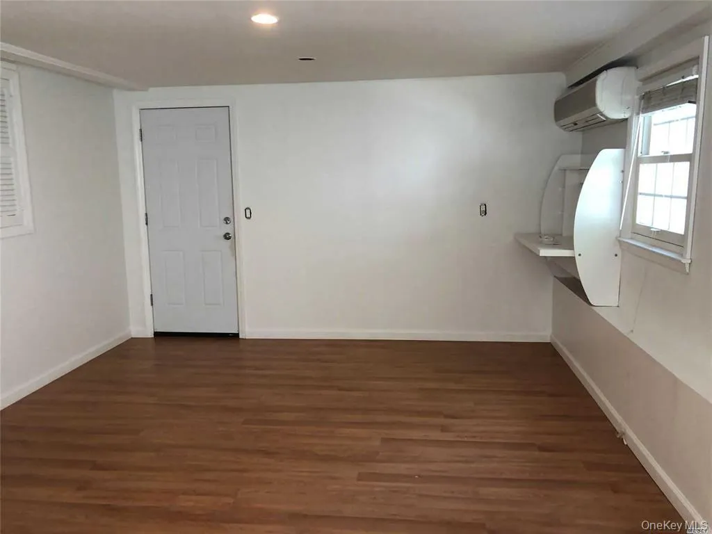 Unfurnished room with a wall mounted air conditioner, dark wood finished floors, and recessed lighting Unfurnished room with a wall mounted air conditioner, dark wood finished floors, and recessed lighting