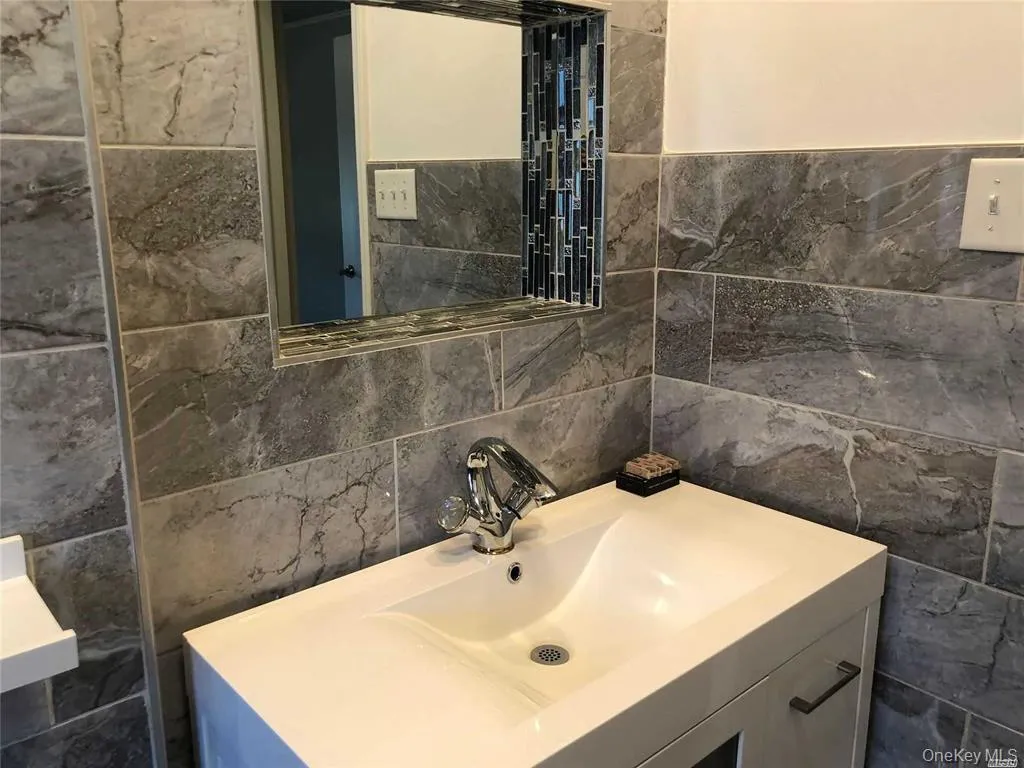 Bathroom featuring vanity and tile walls Bathroom featuring vanity and tile walls