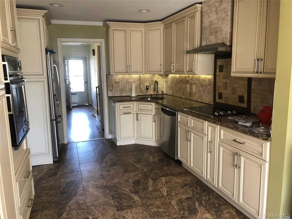 Kitchen with cream cabinets, dark stone countertops, black appliances, and crown molding Kitchen with cream cabinets, dark stone countertops, black appliances, and crown molding