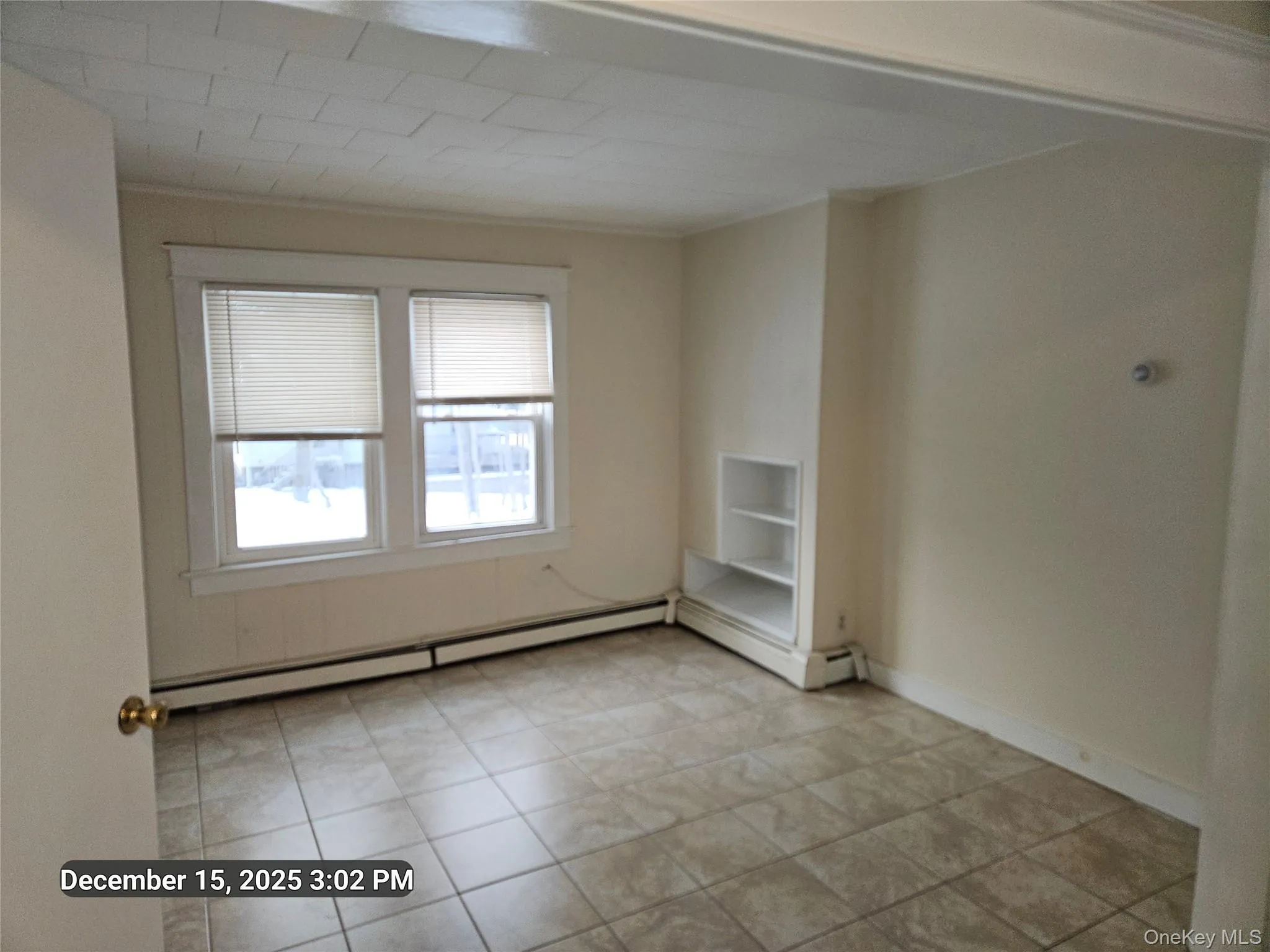 Unfurnished room with a baseboard radiator and light tile patterned floors Unfurnished room with a baseboard radiator and light tile patterned floors