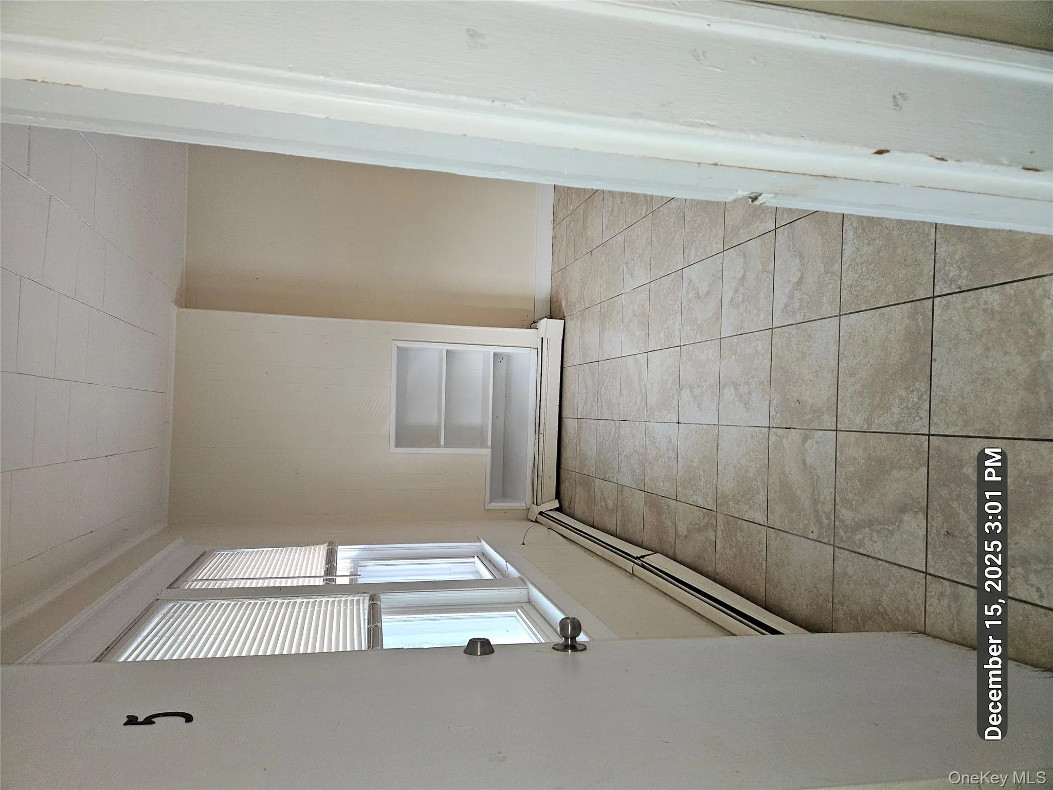 Spare room with light tile patterned floors, built in features, and baseboard heating Spare room with light tile patterned floors, built in features, and baseboard heating