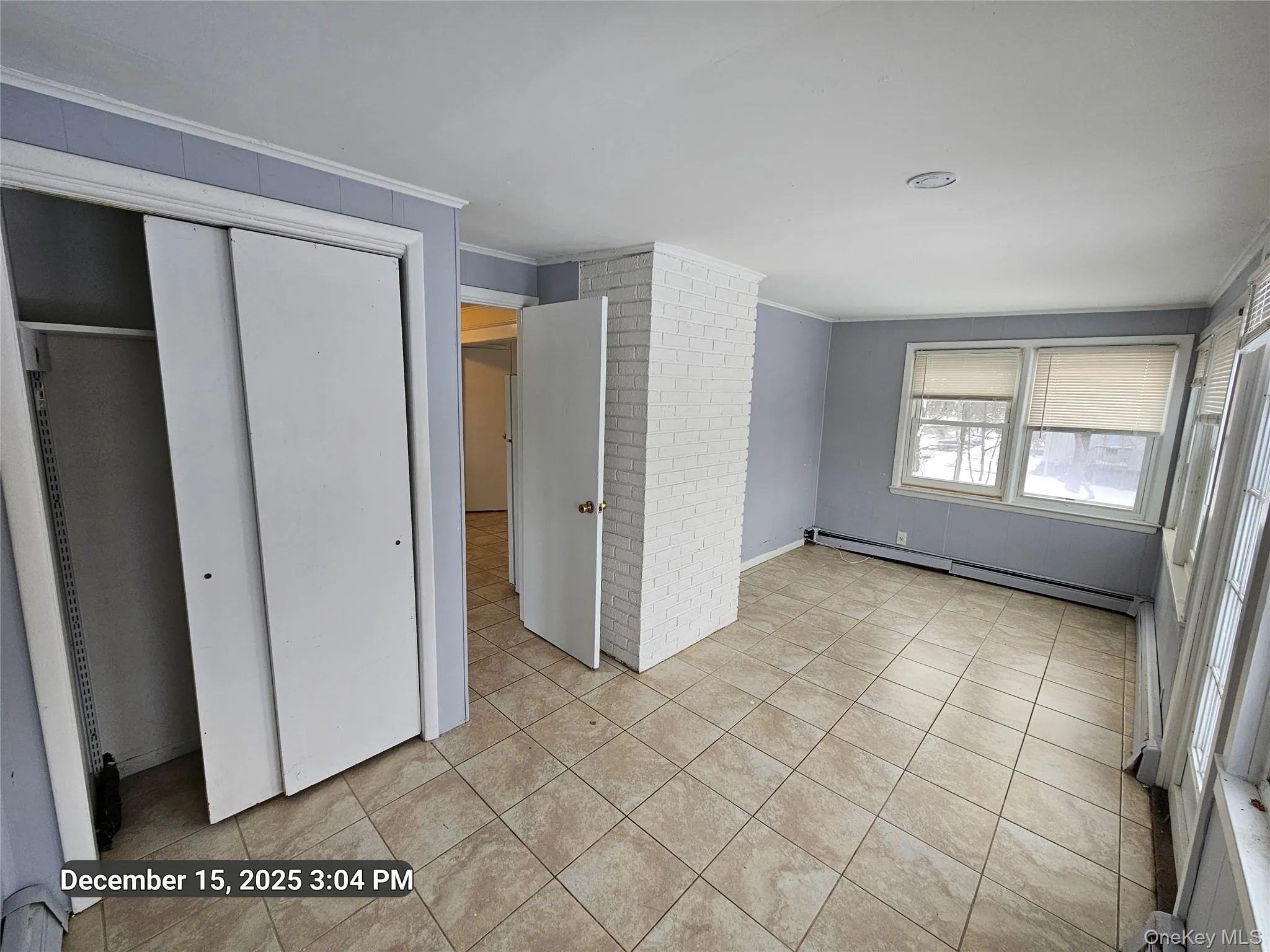 Unfurnished bedroom featuring brick wall, a baseboard heating unit, a closet, and crown molding Unfurnished bedroom featuring brick wall, a baseboard heating unit, a closet, and crown molding