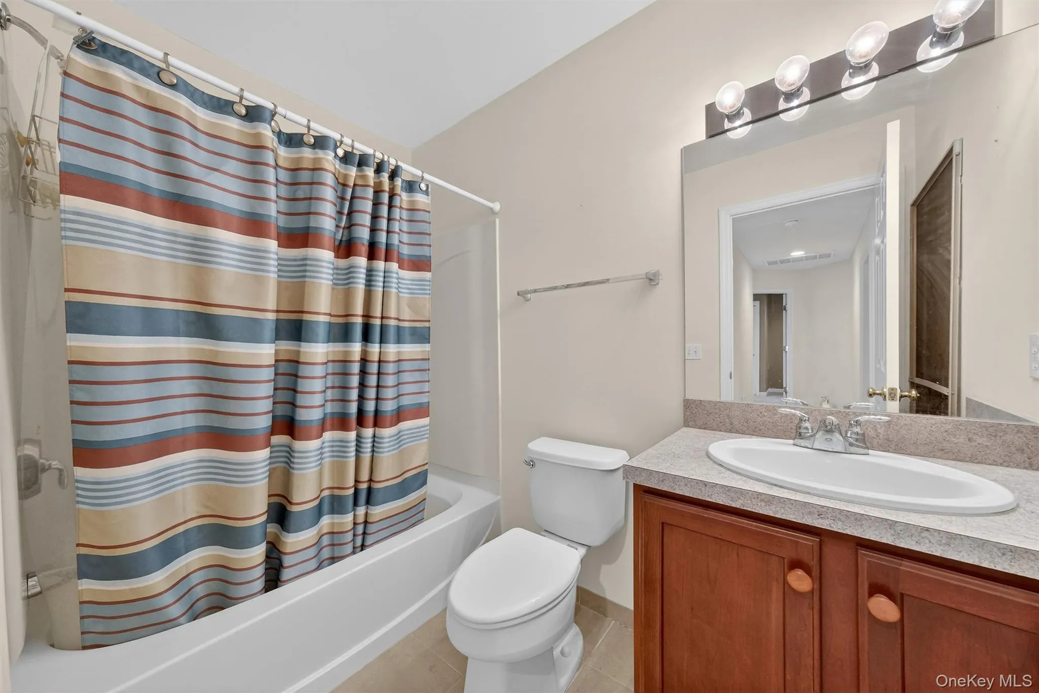Bathroom featuring vanity, shower / tub combo with curtain, and light tile patterned floors Bathroom featuring vanity, shower / tub combo with curtain, and light tile patterned floors